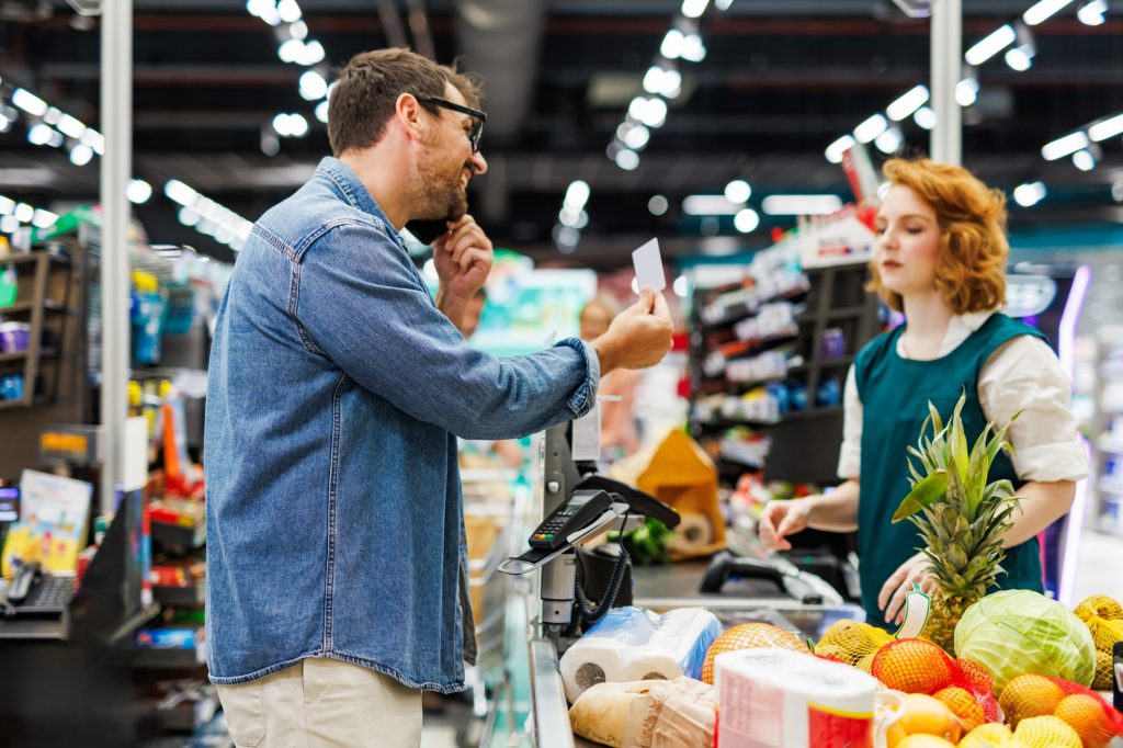Customer making a phone call while paying at the supermarket checkout