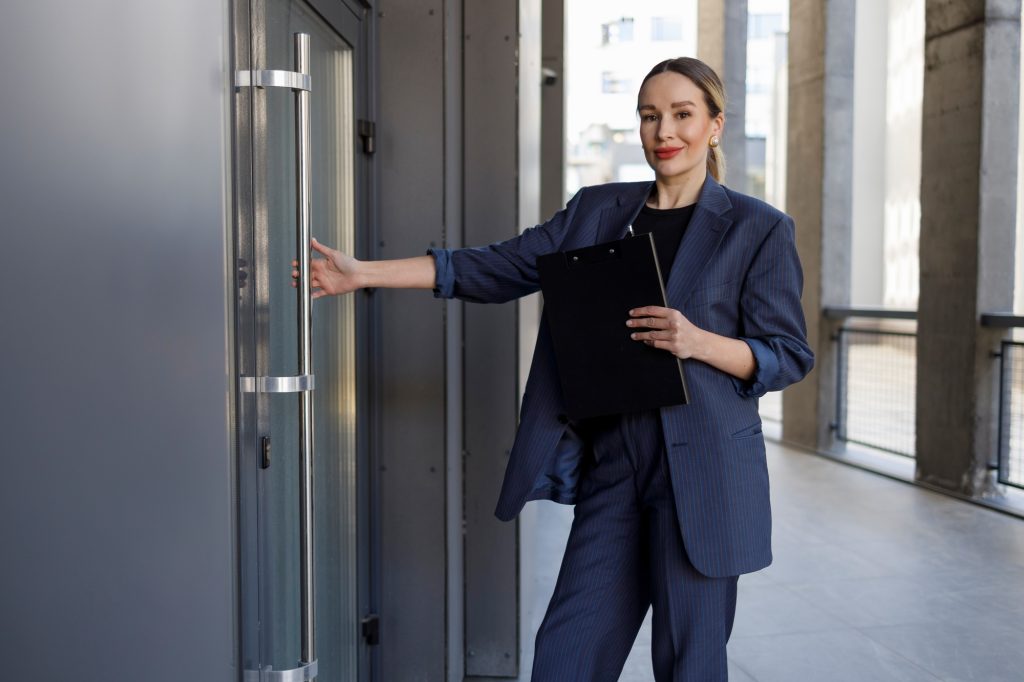 Elegant businesswoman with clipboard opening office door