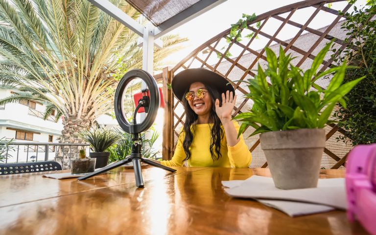 Happy woman having fun doing online video call using smartphone cam and influencer led