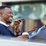 Happy man talking on phone, travel for business in a city, sitting outside while using tech t