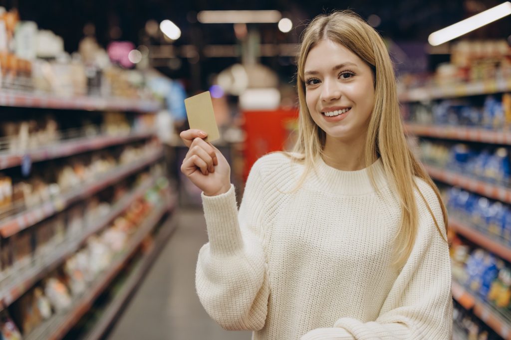 Smiling woman showing loyalty card in supermarket