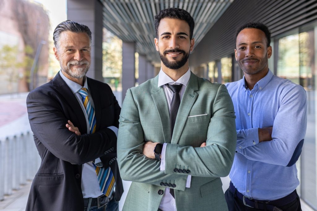 Successful portrait of corporate team of male colleagues looking at camera
