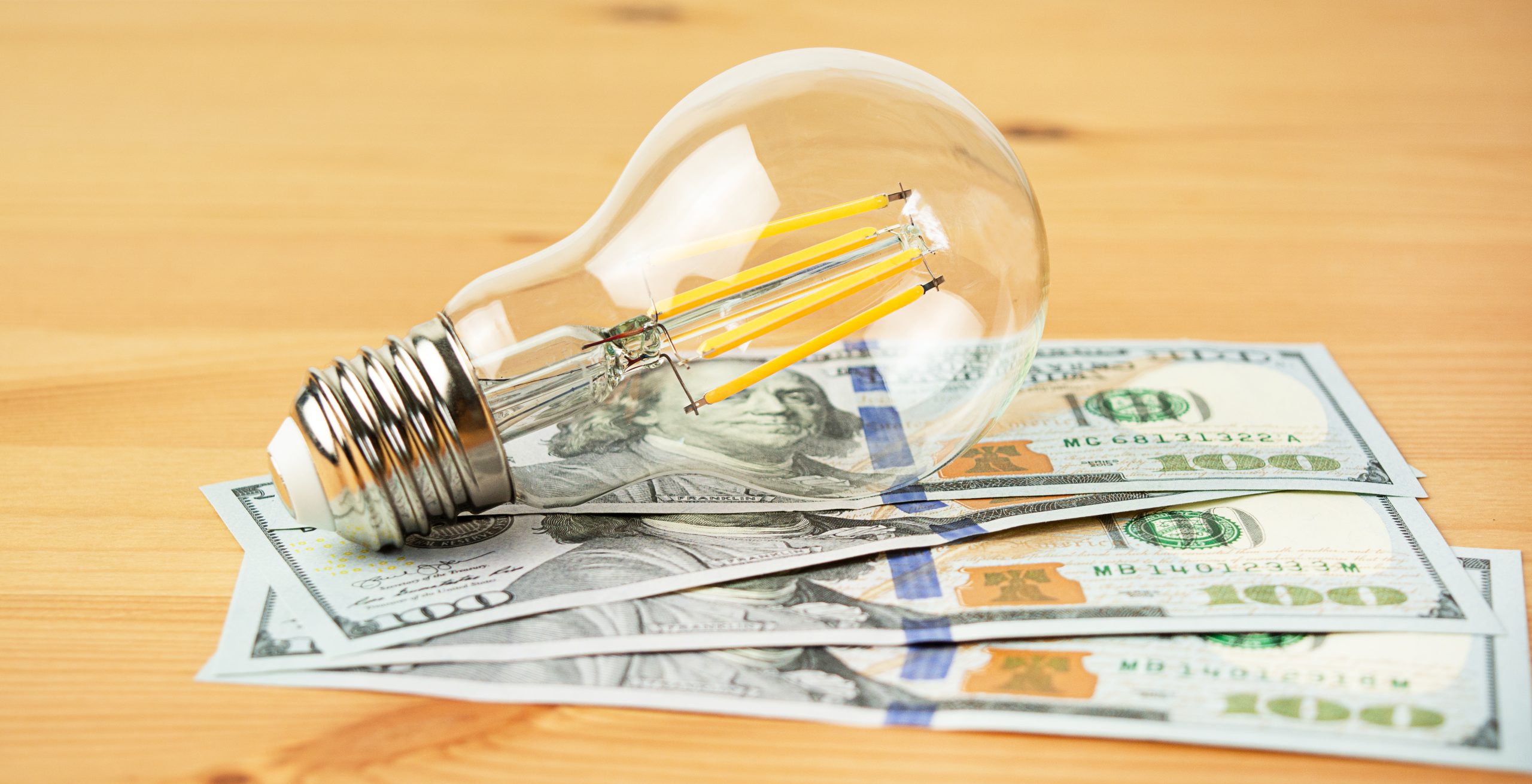 How much does it cost to patent an idea, shown by a lightbulb on hundred dollar bills